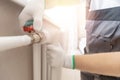 Plumber man is blocking repairs radiators of heating battery in apartment tap