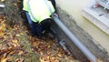 A person carries out plumbing work to replace a water pipe outside the house.