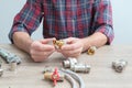 Plumber measures the size of fitting before connecting water pipe. Plumber connects fittings while repairing equipment. Close-up