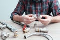 Plumber measures the size of fitting before connecting water pipe. Plumber connects fittings while repairing equipment. Close-up