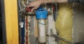 Plumber opens the water supply through the filter with a new clean cartridge. Water fills the filter bowl.