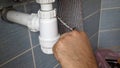 The plumber removes the end cap from the water supply hose. The plumber's hands remove the blanking plug from the