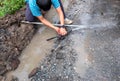 A plumber is repairing a broken pipe and replacing a hole with water on the side of the road.