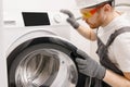 Plumber repairing washing machine, working man fixing problem