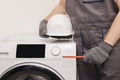 Plumber repairing washing machine, working man fixing problem