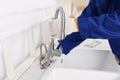 Plumber repairing water tap in kitchen, closeup Royalty Free Stock Photo