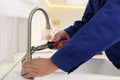 Plumber repairing water tap with wrench in kitchen, closeup Royalty Free Stock Photo