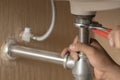 Plumber repairs and maintains chrome siphon under the washbasin in bathroom. Royalty Free Stock Photo