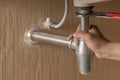 Plumber repairs and maintains chrome siphon under the washbasin in bathroom.