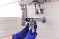 Plumber repairs and maintains chrome siphon under the washbasin. Plumber at work in bathroom, plumbing assemble and