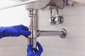 Plumber repairs and maintains chrome siphon under the washbasin. Plumber at work in bathroom, plumbing assemble and