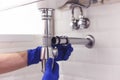 Plumber repairs and maintains chrome siphon under the washbasin. Plumber at work in bathroom, plumbing assemble and