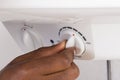 Plumber`s Hand Turning The Knob Of Electric Boiler Royalty Free Stock Photo