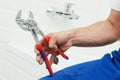 Plumber service. hand with wrench in front of bathroom tap Royalty Free Stock Photo