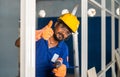 plumber showing thumbs up sign by holding drilling machine at construction site - concept of repair or maintenance