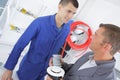 Plumber teaching trainee to connect radiator