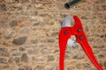 Plumber tools isolated. A red PVC pipe cutter for cutting plastic pipes and a piece of PE pressure pipe or water pipe over stone Royalty Free Stock Photo