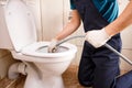 plumber unclogging blocked toilet with hydro jetting at home bathroom Royalty Free Stock Photo