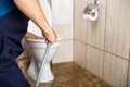 plumber unclogging blocked toilet with hydro jetting at home bathroom Royalty Free Stock Photo