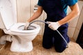 plumber unclogging blocked toilet with hydro jetting at home bathroom Royalty Free Stock Photo