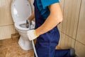 plumber unclogging blocked toilet with hydro jetting at home bathroom Royalty Free Stock Photo