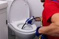 Plumber unclogging blocked toilet with hydro jetting at home bathroom. sewer cleaning service