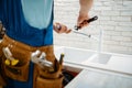 Plumber in uniform fixing faucet in the kitchen Royalty Free Stock Photo