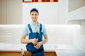 Plumber in uniform fixing faucet in the kitchen Royalty Free Stock Photo