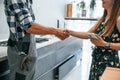 Plumber in uniform helped woman on the kitchen. Doing handshake