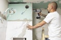 Plumber using electric screwdriver. Bathroom renovation concept. Marble ceramic tiles with spacers and grey cement walls in Royalty Free Stock Photo