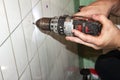 Plumber using grungey old drill to drill hole on vintage bathroom tile - closeup of hands Royalty Free Stock Photo