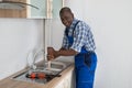 Plumber Using Plunger In Kitchen Sink Royalty Free Stock Photo