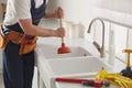 Plumber using plunger to unclog sink drain in kitchen, closeup Royalty Free Stock Photo