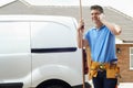 Plumber With Van Making Call On Mobile Phone Outside House