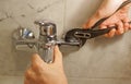 Plumber At Work Fixing Bath Faucet With A Spanner 