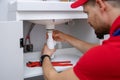 Plumber working in bathroom installing sink siphon