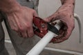 Plumber working man cuts urgently dirty hands white pipe to repair the aqueduct.