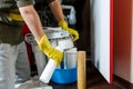 Plumber in yellow household gloves changes water filters. Repairman installing water filter cartridges in kitchen.