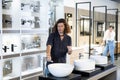 in plumbing department,thoughtful man inspects round white ceramic sinks with faucets