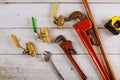 Plumbing gate ball vales, fixtures on monkey wrench and tape measure on wooden board Royalty Free Stock Photo