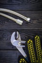 Plumbing tools and gloves for connecting water hoses on a black wooden background Royalty Free Stock Photo
