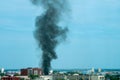 Plume of black smoke from a fire above city at sunset. Technogenic accident Royalty Free Stock Photo