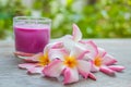 Plumeria (Frangipani) flowers, Purple candles in glass and spa stone on wooden background. Royalty Free Stock Photo