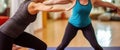 Plump female personal instructor in activewear helping woman with stretching body during yoga class. Generative AI