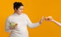 Plump girl refusing junk food, holding bowl with fresh vegetable salad Royalty Free Stock Photo