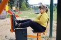 Plump girl sits on street simulator in thought, motivation of healthy lifestyle, sports exercises