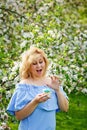 A plump girl in a spring blooming park wants to eat a cake. Girl plus size and sweet