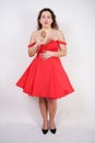 Plump woman in a red pinup dress. chubby fashionable girl standing on white background in Studio Royalty Free Stock Photo