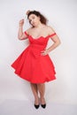 Plump woman in a red pinup dress. chubby fashionable girl standing on white background in Studio Royalty Free Stock Photo
