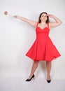 Plump woman in a red pinup dress. chubby fashionable girl standing on white background in Studio Royalty Free Stock Photo